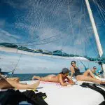 Experience four people relaxing aboard the Summer Jo Day Charter sailing boat beneath a bright blue sky with wispy clouds over the sea.