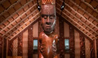 Intricately tattooed wooden Māori carving in a traditional meeting house at Waitangi Treaty Grounds, historic site in New Zealand.