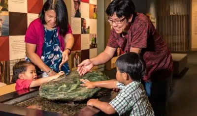 A family of four discovers a grand stone exhibit inside Waitangi’s renowned indoor museum in New Zealand, learning local history.