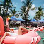 Woman lounging on a vibrant pink flamingo float at The Great Escape 21 Day Semi-Guided Group Tour from Brisbane to Cairns, Australia.
