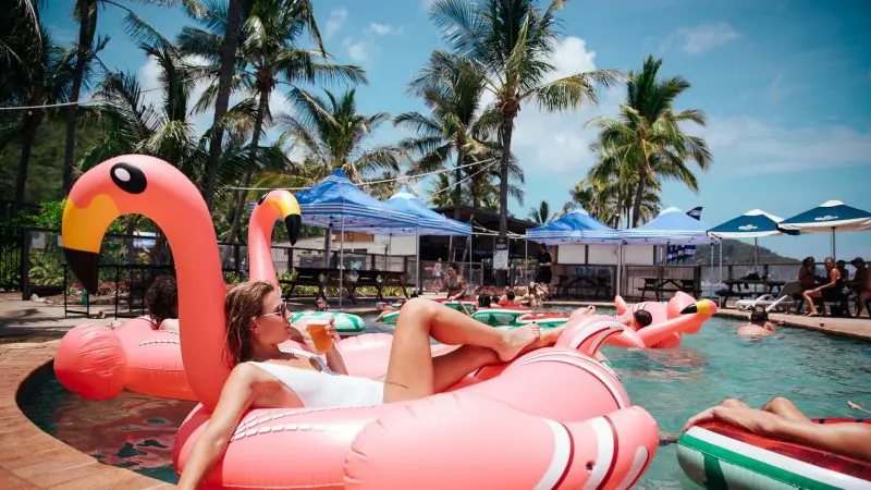 Woman lounging on a vibrant pink flamingo float during The Great Escape Australia 28 Day Semi-Guided Adventure, enjoying the sun.