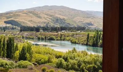 Scenic river meandering through lush green fields and rolling hills beneath a clear blue sky—idyllic setting for boutique wine tours.