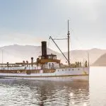 Vintage steamship cruising a serene lake with scenic mountains in the background—ideal setting for top-rated classic wine tour cruises.