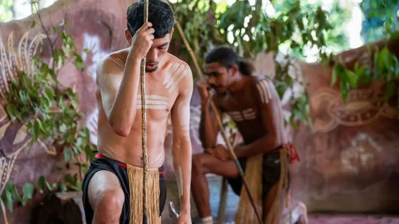 Two men in vibrant body paint and traditional dress attend an exclusive outdoor Grand Kuranda cultural ceremony for VIP guests.