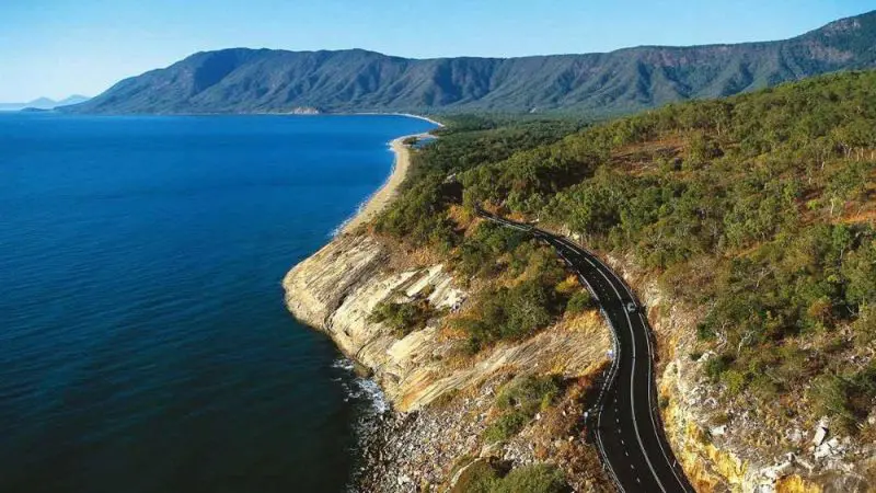 Scenic winding coastal road hugging the rocky Daintree shoreline, ideal for a private exclusive Cape Tribulation tour experience.