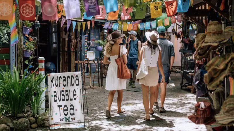 Visitors explore vibrant stalls adorned with colourful flags at Kuranda Bubble Tea during a 3 Day Daintree Cape Tribulation Tour.