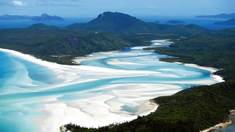 Spectacular aerial view of vibrant turquoise waters weaving through pristine white sands on a Sydney to Cairns, Fraser Island tour.