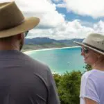 Two travellers in sun hats admire a breathtaking bay view—ideal for a 14 Day Sydney to Cairns with Fraser Island Whitsundays Comfort Tour.