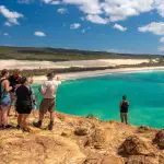 Travellers on the 8 Day Sydney to Brisbane with Fraser Island Comfort Tour admire stunning turquoise waters and lush forest from a scenic cliff.