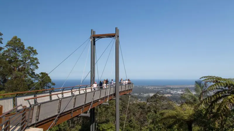 Tour group on scenic lookout bridge admires stunning coastline during 14-Day Sydney to Cairns Tour with Fraser Island Whitsundays views.