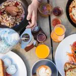 Sumptuous breakfast spread on a table as tea is poured, inviting you to start your 8 Day Sydney to Brisbane Fraser Island tour.