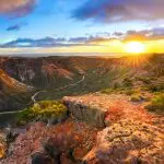 Breathtaking sunrise illuminates a dramatic canyon on the 8-Day Perth to Exmouth Comfort Tour, showcasing iconic coast and cliffs.