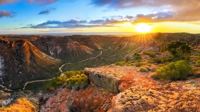 Breathtaking sunrise illuminates a dramatic canyon on the 8-Day Perth to Exmouth Comfort Tour, showcasing iconic coast and cliffs.