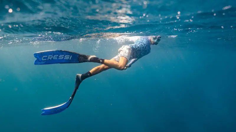 Snorkeller in blue fins glides through crystal-clear Ningaloo Reef waters on an immersive 8-day Perth to Exmouth adventure tour.