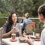 A man and woman savour gourmet meals and drinks at a scenic outdoor café, reliving their 1 Day Grampians Eco Wilderness Escape tour.