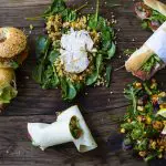 A tempting spread of gourmet sandwiches, fresh wraps, and vibrant salads on a rustic table—ideal prelude to your Peninsula Hot Springs Spa Entry Shuttle Bus experience.