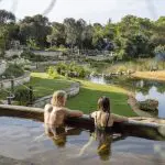 Two people unwind in a natural hot spring pool after a Peninsula Hot Springs Spa day tour with shuttle bus, enjoying ultimate relaxation.