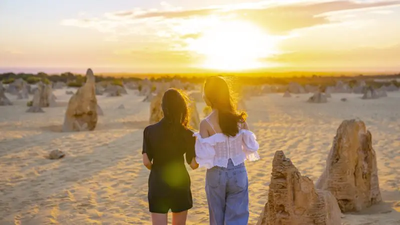 Two women exploring the Pinnacles Desert at sunset during a 1 Day Lobster Lavender Tour from Perth, Western Australia.