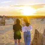 Experience the breathtaking 1 Day Pinnacles Sunset Stargazing Tour by Autopia as two travellers explore sandy desert dunes at sunset.