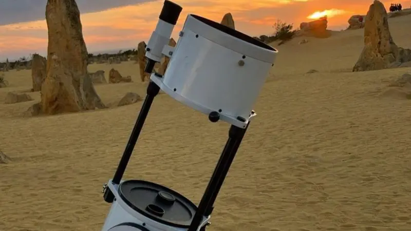 A white telescope on sandy terrain captures a stunning sunset during the 1 Day Pinnacles Sunset Stargazing Tour by Autopia.