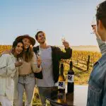 Four friends clink wine glasses at sunset in a lush Hunter Valley vineyard, smiling during a premium 1 Day Scenic Wine Tour.