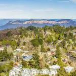 Stunning aerial view of a charming Blue Mountains town, ideal for sunset wilderness tours, beneath a vibrant clear blue sky.