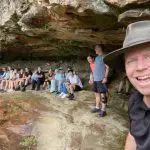 A cheerful man in a hat snaps a selfie with friends amid scenic landscapes on a 1 Day Blue Mountains Sunset Wilderness Tour outdoors.