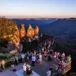 Travellers marvel at the iconic Three Sisters formation at sunset from a Blue Mountains lookout on a top-rated 1 Day Wilderness Tour.