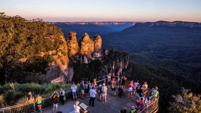 Travellers marvel at the iconic Three Sisters formation at sunset from a Blue Mountains lookout on a top-rated 1 Day Wilderness Tour.