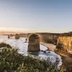 Breathtaking sunrise over the Twelve Apostles cliffs, waves crashing below on a top-rated Great Ocean Road tour from Melbourne.