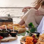 Gourmet table with assorted fruit, premium cheeses, and snacks on a luxury boat at sunset during Sydney Harbour Golden Glow Cruise.