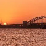 Stunning Sydney Harbour Bridge and Opera House bathed in golden sunset glow, ideal backdrop for top-rated Sydney Harbour sunset cruise.