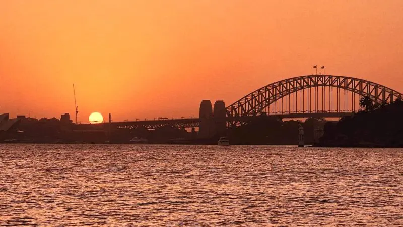 Stunning Sydney Harbour Bridge and Opera House bathed in golden sunset glow, ideal backdrop for top-rated Sydney Harbour sunset cruise.