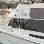 Three friends converse on Heaven on the Water’s deck during a Sydney Harbour Golden Glow Sunset Cruise, city skyline in the background.