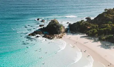 aerial view of a headland with breaking waves and surfers in the water