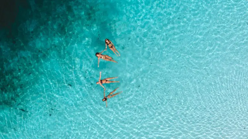 A group of friends floating in the clear waters of Lake Mckenzie