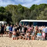 backpackers exploring K'gari at the beach with a bus in the background