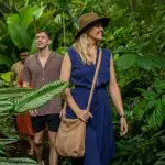 Two people smile as they walk among lush tropical plants on a CSHD Tour, with more following in Cairns City.