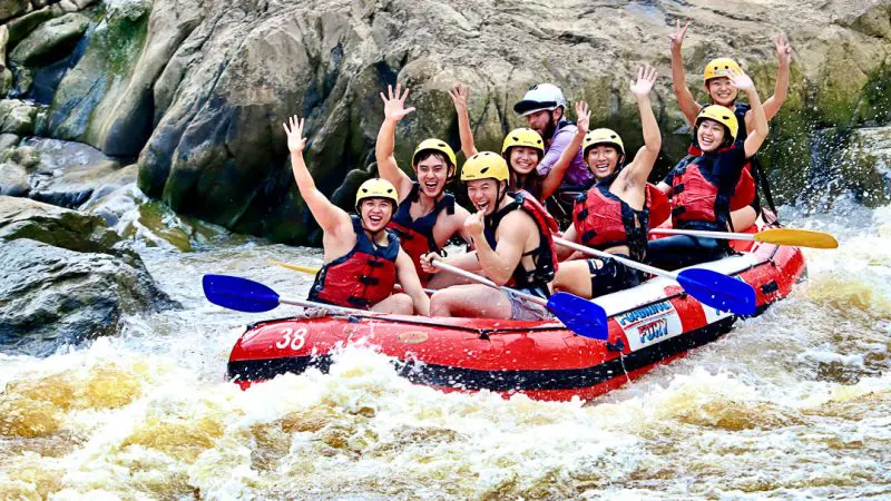 a group of friends in an inflatable river raft floating down a fast flowing river