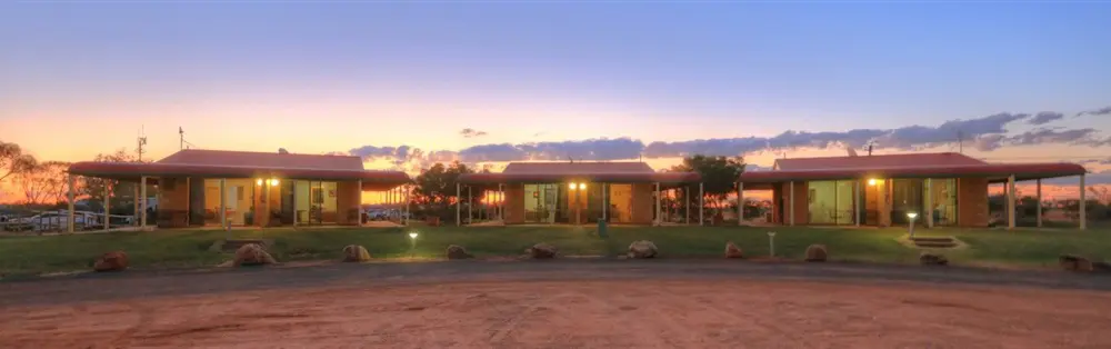 3 small cabins at sunset with red desert around them