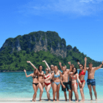 a group of backpackers having fun on a beach with an island in the background
