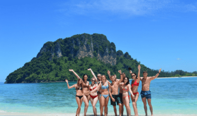 a group of backpackers having fun on a beach with an island in the background