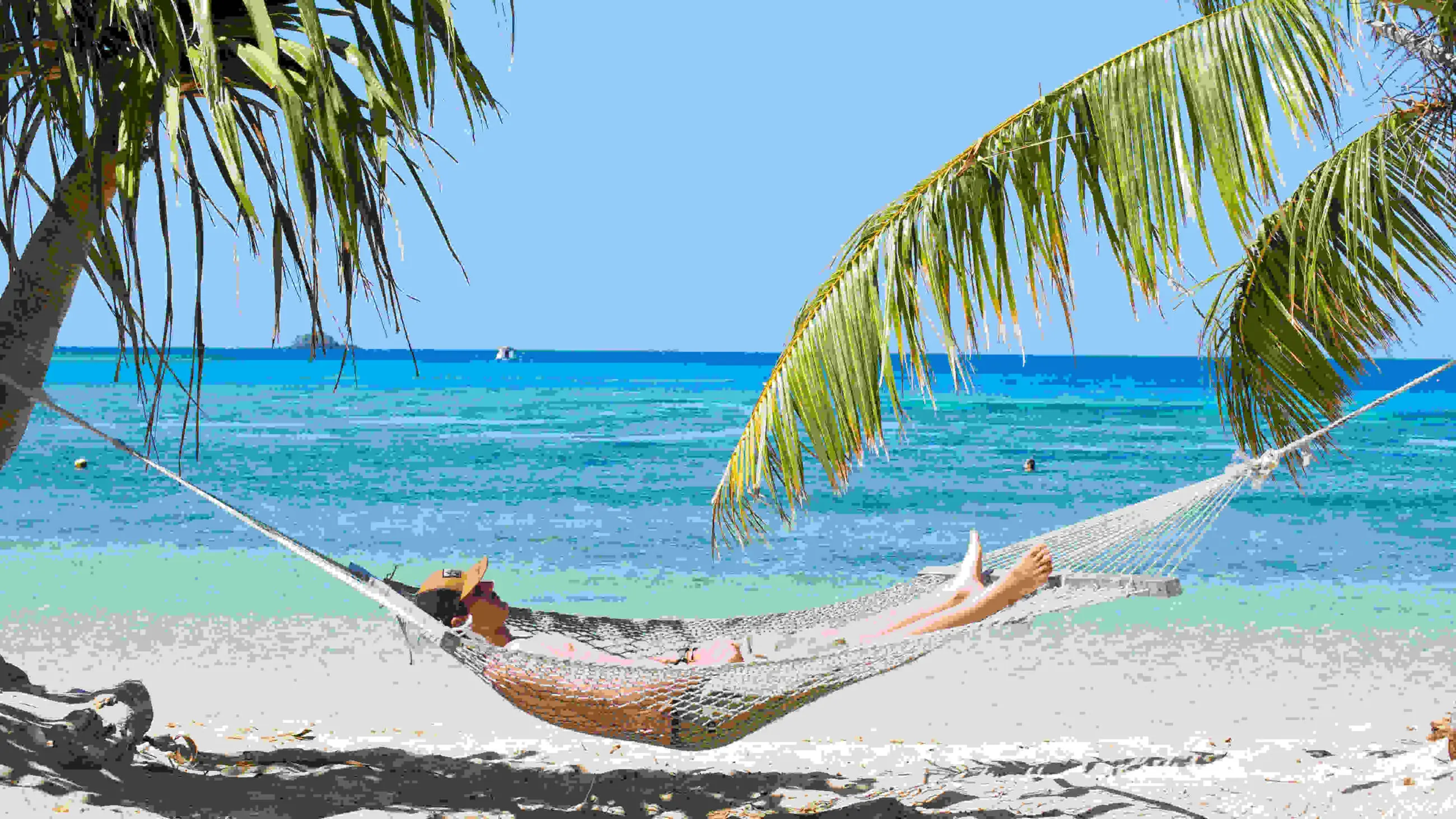 a man Chilling in a hammock on a beach with ocean in the background