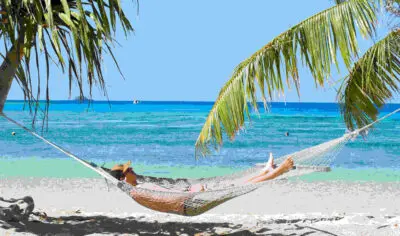 a man Chilling in a hammock on a beach with ocean in the background