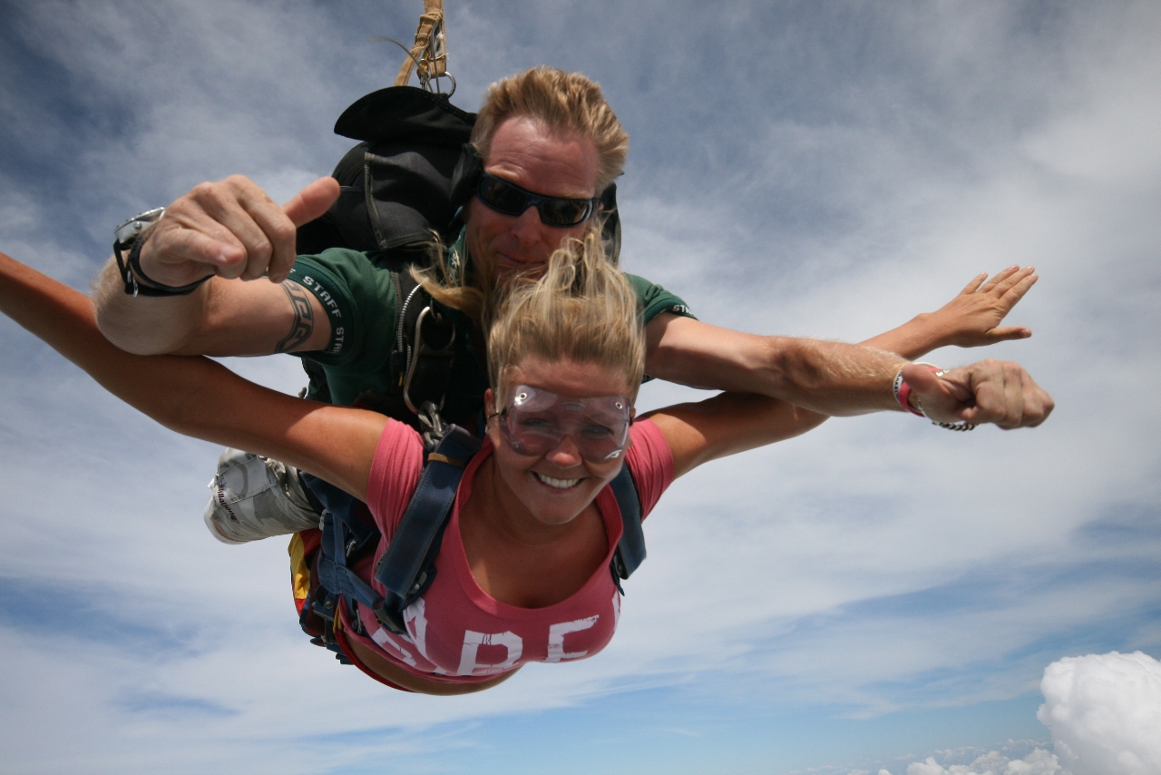 Two people tandem skydiving over Sydney, smiling and giving thumbs up above the clouds—experience top-rated Skydive Extras.