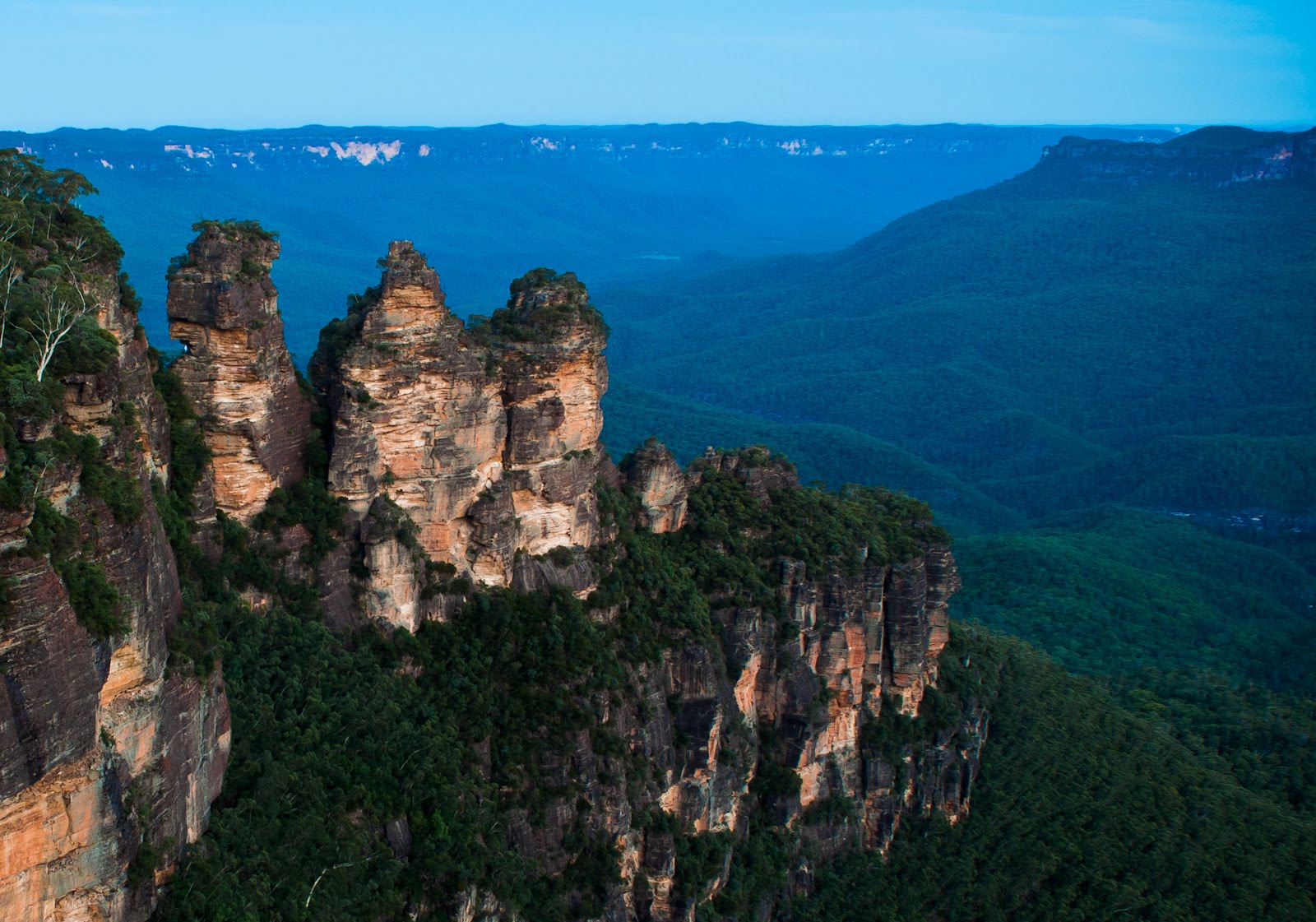 The iconic Three Sisters sandstone peaks tower over lush forest in Australia’s Blue Mountains, a must-see on 1 Day Blue Mountains Tours.