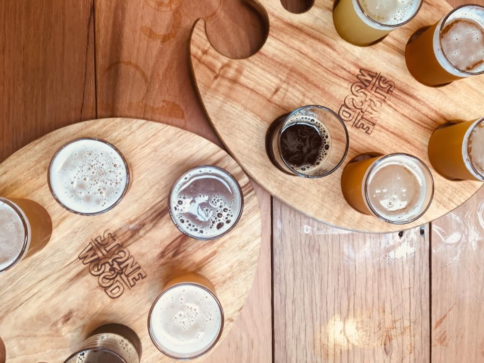 Craft beer tasting experience featuring wooden paddles with assorted glasses, ideal for a full day brewery and distillery tour.