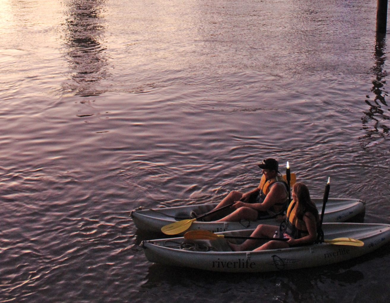 Two kayakers with bright yellow paddles float on calm waters at sunset—Friday or Saturday night tours only, no catering included.