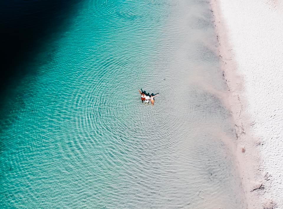 Experience two people floating in crystal-clear turquoise waters by a pristine sandy beach on a 3 Day K'gari Tour from Rainbow Beach.