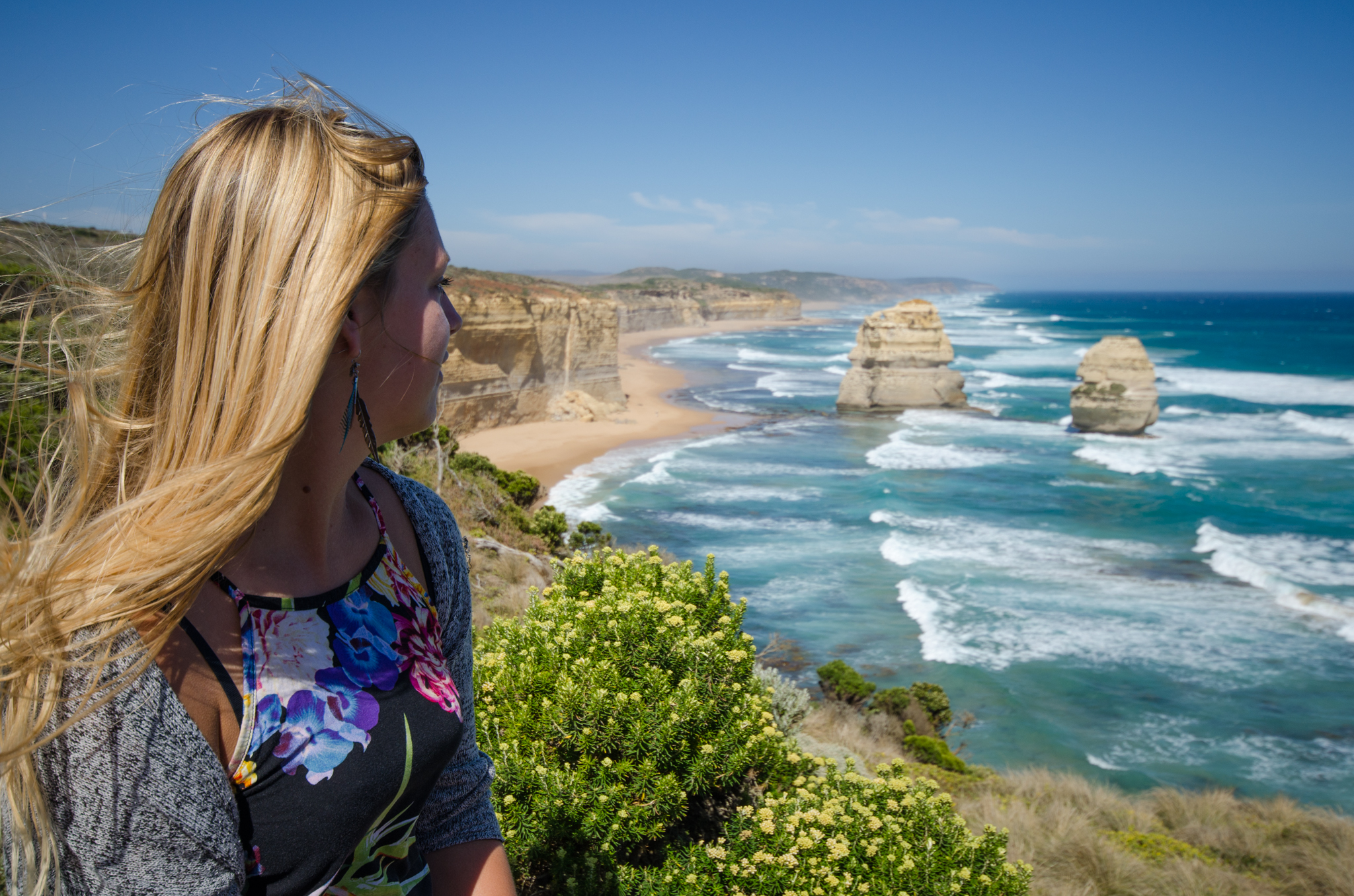 Blonde woman gazes at dramatic ocean cliffs during the 3 Day Great Ocean Road Melbourne to Adelaide Explorer tour, scenic coastline views.